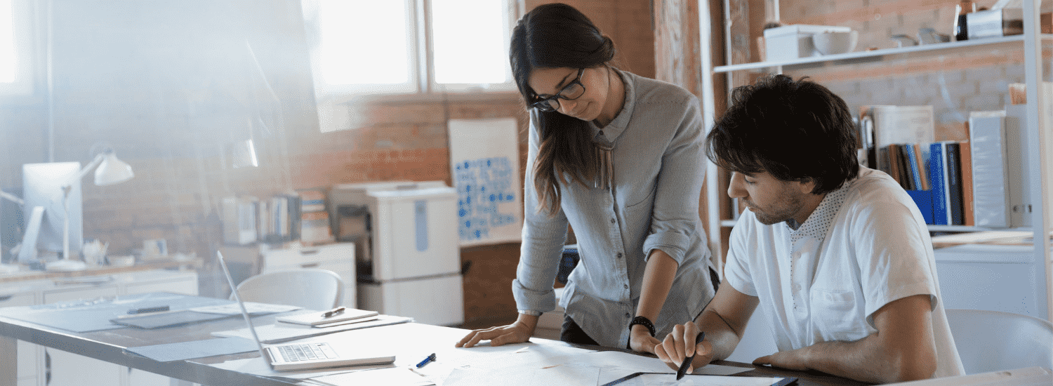 man and woman looking at a desk in office